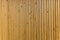 Vertical thin wooden slats on wall in modern interior. Natural brown color