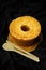 Vertical top view of Chiffon cake on wooden board and wooden cutlery on black satin background