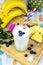 Vertical top view of an iced drink with blueberries on it with  bananas ananas on the board