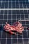 Vertical top view of red cable reel and a screwer leaning on a solar panel installation for renewable energy source