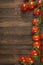 Vertical top view of red tomatoes on a vine on a wooden background with copy space