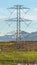 Vertical Towering power lines in the valley against snow capped mountain and blue sky