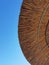 Vertical undershot of a straw umbrella and blue sky in the background