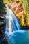 Vertical up close shot of waterfall pouring over canyon into blue pond