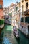 Vertical Venice picture with a canal and tourists on a gondola