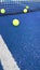 Vertical video, balls bouncing on a blue paddle tennis court