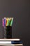 Vertical video of composition of crayons in container on stack of books on grey background