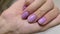 Vertical video with womans hand with trendy fashionable lavender manicure on gray background. Nail design trends