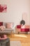 Vertical view of beautiful suede covered cabinet with black fancy vase next to fashionable grey couch with pastel pink pillow and
