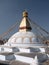 Vertical view of buddhist stupa with prayers flags and a yellow lotus painted in the dome.