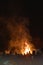 Vertical view of the crowd standing before the roaring bonfire flames at night