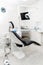 Vertical view of a dentist room with black seat. Modern dental practice. Dental chair and other accessories used by