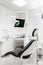 Vertical view of a dentist room with black seat. Modern dental practice. Dental chair and other accessories used by