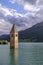 Vertical view of the famous bell tower of old Curon, submerged in the Resia lake, South Tyrol, Italy