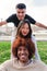 Vertical view of group of three multiracial young friends having fun and smiling looking at camera. Front view of happy