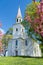 Vertical view of the historic Old School Baptist Meeting house flanked by flowering trees located in