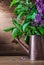Vertical view lilac flowers in vintage watering can on wood