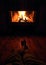 Vertical view of a man's feet laying on the wooden flor in front of the fireplace