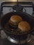 Vertical view of mini veggie hamburgers being heated up in a frying pan.