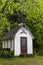 Vertical view of minuscule old brown and white wooden rural chapel nestled in tree