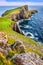 Vertical view of Neist Point lighthouse and rocky ocean coastline, Scotland
