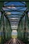 Vertical view through old, iron, railway bridge during sunset