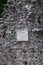 Vertical view of an old stone wall with a panel representing the monument building purpose