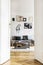 Vertical view of open door to living room interior with grey sofa, industrial coffee table and golden chandelier