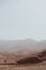 Vertical view of rocky sand dunes in the dusty desert with blurry sky background