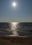 Vertical view of a sandy beach and gentle ocean under a blue sky with a sun star and text The Baltic Sea written in the sand