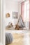 Vertical view of scandinavian kids bedroom with tent, toys, pillows and painting on the wall, real photo