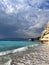 Vertical view of sea waves reaching the cliffs of the shore under the cloudy sky