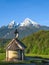 Vertical view of small chapel and snowy summit of Watzmann mount