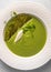 Vertical view soup puree of green peas and coconut milk with tuil and cheese quenelle