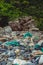Vertical view Spilled garbage on stones near beautiful natural park composition, gray rock shabby cliff cracks