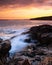 Vertical view of sunset at Otter Point in Acadia National Park. Waves crashing on