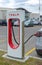 A Vertical view of a Tesla Supercharger stall with charging cable-outlet charging an electric car.