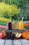 A vertical view of three bottles of fruit juice including apple, orange and grape, against a garden background.