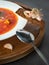 Vertical view to red ukrainian borscht in white plate on wooden plate with lard on dark bread