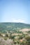 Vertical view into Tuscany country. Land is covered by trees, vineyards, olive alleys and few farm houses. Hill in background is