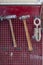 Vertical view of two old hammers with a brown wooden handle and a clamp hanging on the wall in a workshop for carpentry work on a