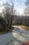 Vertical view of where a stone road ends and a mountain road begins with a bend and forest