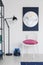 Vertical view of white chair with pink pillow in white interior with moon graphic on the wall and metal lamp, real photo