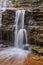 Vertical waterfall detail over dark brown rock cliffs