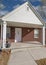 Vertical White puffy clouds Exterior of a small house with red bricks and white door