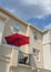 Vertical White puffy clouds Red umbrella on a balcony of a townhouse with cream wall exterio