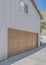 Vertical White puffy clouds Uphill curved driveway beside the garage with sliding window and white texture bricks wall