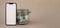 Vertical White screen on modern mobile phone in background of glass jar full of American currency dollar banknotes on