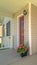 Vertical Wicker armchairs on the sunlit front porch of home with brown front door