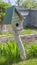 Vertical Wooden birdhouse and vibrant green plants at the sunny garden of a home